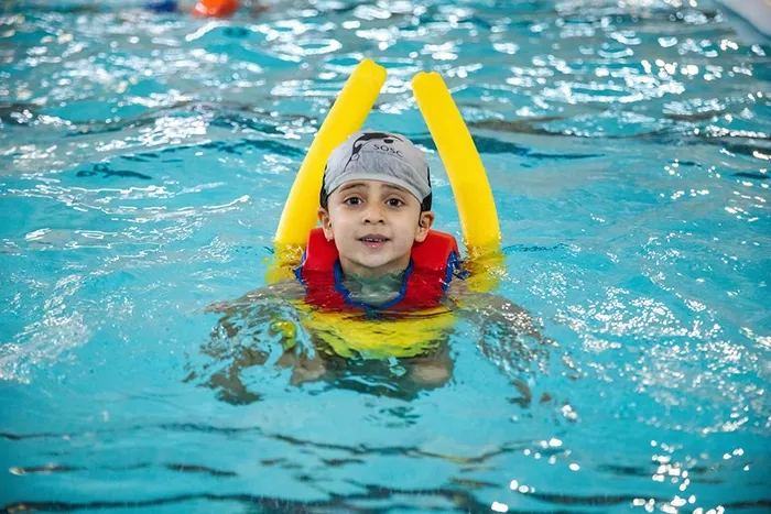 Child swimming with pool noodles during Ockendon Holiday Camp at Harris Academy Ockendon